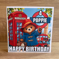 Paddington Bear personalised 6x6 birthday card with name Poppie age 4 and colourful London bus and telephone box design
