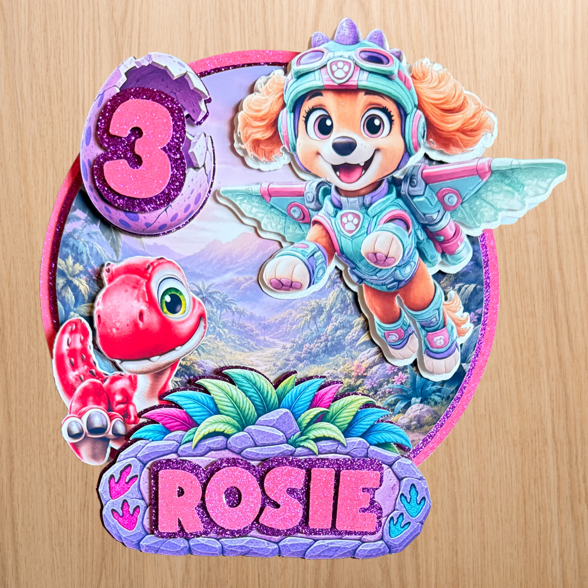 Personalised Skye dinosaur cake topper with the name Rosie and age 3 in pink, purple and glitter colours